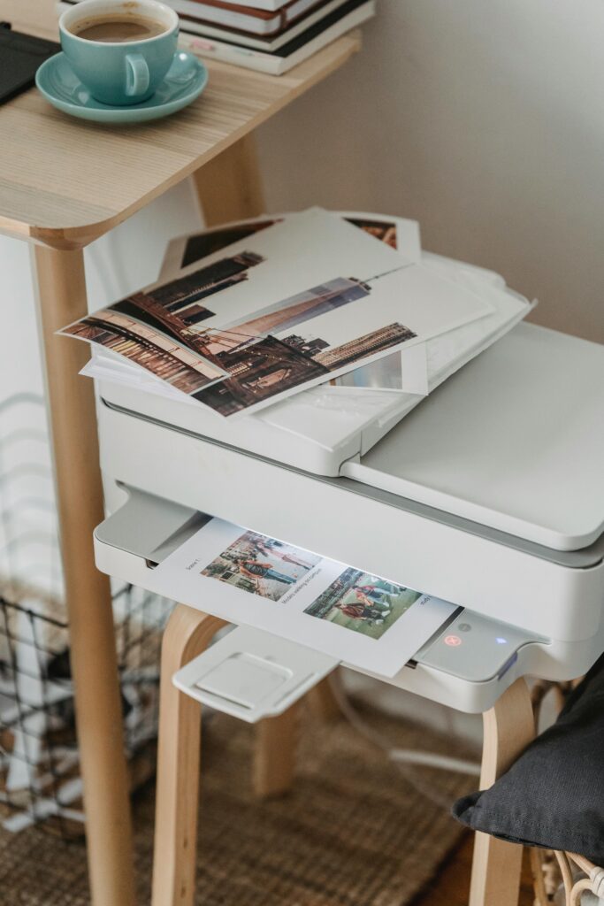 From above of images placed on printer on wooden table with cup of hot coffee at workplace